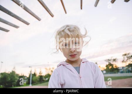 Bébé en colère. Portrait of cute adorable petit blond Caucasian girl child making funny faces stupides. Jeu pour Enfants s'amusant à l'extérieur du parc au coucher du soleil. T Banque D'Images