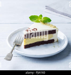 Gâteau au chocolat blanc avec feuille de menthe fraîche sur une assiette. Fond de bois. Banque D'Images