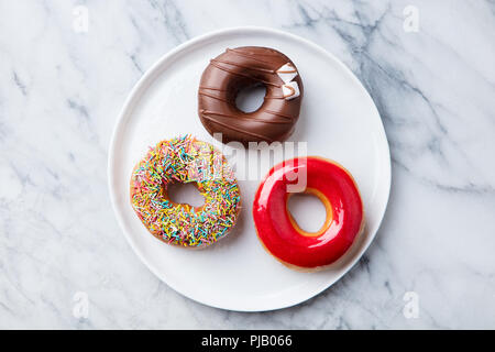 Assortiment des beignets avec des vernis sur plaque blanche. En arrière-plan. Vue d'en haut. Banque D'Images