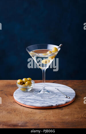 Cocktail Martini aux olives vertes sur en conseil. Table en bois. Fond bleu. Banque D'Images