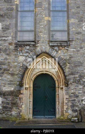 Porte double en arc sur charnières en métal sur la paroi latérale de la cathédrale médiévale en pierre. Banque D'Images