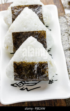 Onigiri. Triangle de riz avec nori seaweed sur plaque blanche. Banque D'Images