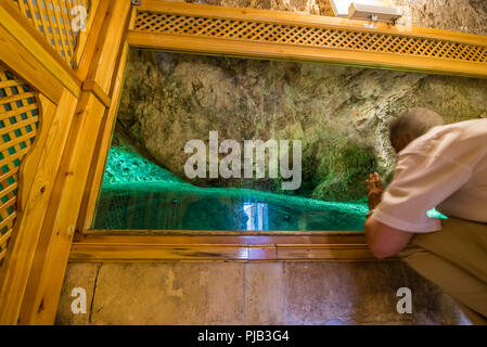 Homme non identifié prie en grotte où le prophète Abraham est né à la cour intérieure de la mosquée Mevlidi Halil à Sanliurfa, en Turquie. Banque D'Images