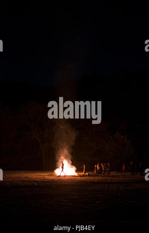 Une foule de gens debout autour d'un grand feu qui s'allume sur une sombre nuit d'hiver, dans les Cevennnes, France Banque D'Images