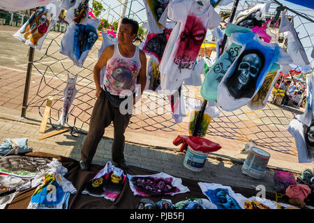 Un homme vend des t-shirts, avec divers Santa Muerte (sainte mort) images, dans la rue au cours d'un pèlerinage dans la ville de Mexico, Mexique. Banque D'Images