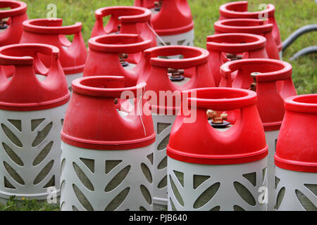 Les bouteilles de gaz de composite couleur gris et rouge dans le volume de 18,2 litres en herbe se tiennent sur un parc de la ville pour l'exécution d'action coloré avec la lumière et la musique Banque D'Images