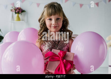 Portrait of happy child holding gift box près de ballons Banque D'Images