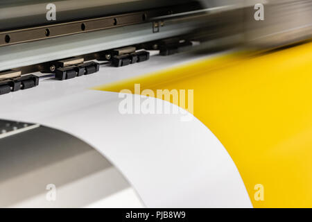 Détail de grande tête d'impression jaune passant sur des rouleaux de papier glacé. Banque D'Images