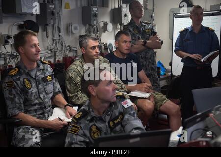 Océan Pacifique (11 juillet 2018) Les marins de la Royal Navy, l'US Navy, de la Royal Australian Navy et de la Marine royale du Canada, de se rassembler dans le bureau logistique tactique à bord du navire de débarquement quai amphibie USS Harpers Ferry (LSD 49), au cours d'une brève mise à jour de commande, à l'appui de Rim of the Pacific (RIMPAC), le 11 juillet. Vingt-cinq nations, 46 navires, 5 sous-marins, environ 200 avions et 25 000 personnes participent à l'EXERCICE RIMPAC du 27 juin au 2 août dans et autour des îles Hawaï et la Californie du Sud. Le plus grand exercice maritime international, de l'EXERCICE RIMPAC, fournit un ensemble unique de traini Banque D'Images