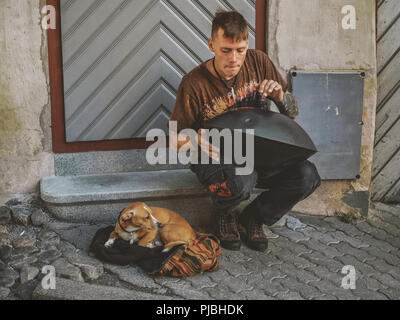 Jeune garçon jouant son hang drum dans les rues de la vieille ville de Tallinn, Estonie. Son chien est lui tenant compagnie. Banque D'Images