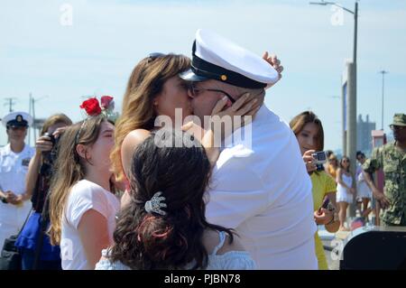 La NORFOLK (11 juillet 2018) Chef Technicien électronique Mark Eichenlaub, affecté à la Virginia-classe sous-marin d'attaque USS John Warner (SSN 785), et sa femme partagent le premier baiser d'honneur à leurs retrouvailles à la fin d'un déploiement de six mois. John Warner est retourné à son port d'attache à Norfolk Naval Station après avoir réussi une mutation à la sixième flotte américaine zone d'opérations. Banque D'Images