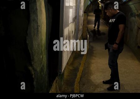 Lance le Cpl. Armando Sajbin, un carabinier avec l'Équipe de débarquement du bataillon, 2e Bataillon, 5ème Marines, se lit un signe dans les tunnels de l'ancien siège de l'underground de La marine japonaise au cours d'une Marine Corps Community Services-parrainé guidée de quelques importants points d'intérêt dans le sud de l'Okinawa, Japon, Juillet 13, 2018. Sajbin, originaire de San Antonio, est diplômé de l'école secondaire d'Eisenhower en 2012 avant de s'enrôler en décembre 2015. Les tunnels du siège situé près de 4 000 défenseurs japonais pendant la bataille d'Okinawa et ouvert au public comme un monument et mémorial en Marc Banque D'Images