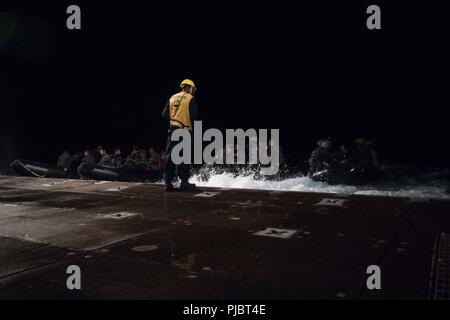 Océan Pacifique (Juillet 15, 2018) Maître de Manœuvre 2e classe Tyrone Hall, de Cleveland, Ohio, affecté à l'amphibious landing ship dock USS Harpers Ferry (LSD 49), observe que quatre raids en caoutchouc de combat de plaisance partent le stern gate, le 15 juillet, à l'appui de la Rim of the Pacific (RIMPAC). Vingt-cinq nations, 46 navires, 5 sous-marins, environ 200 avions et 25 000 personnes participent à l'EXERCICE RIMPAC du 27 juin au 2 août dans et autour des îles Hawaï et la Californie du Sud. Le plus grand exercice maritime international RIMPAC, fournit une formation unique whil Banque D'Images