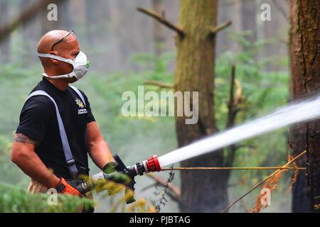 Membre de l'incendie et de secours de Suffolk combat un feu près de Brandon, en Angleterre, le 13 juillet 2018. Le Service d'incendie et de sauvetage de Suffolk a reçu l'appui de la 48e Escadron de génie civil à la Royal Air Force Lakenheath et autres services d'urgence dans la région. Banque D'Images