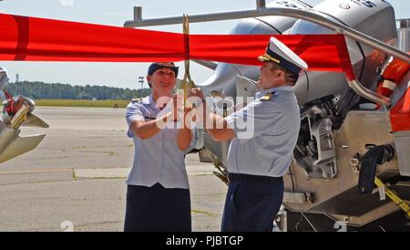 Le lieutenant Cmdr. Anna Hart, commandant de la sécurité maritime et la sécurité, l'équipe de Cape Cod et le Capitaine Mark Walsh couper un ruban au cours d'une cérémonie qui a officiellement reconnu le déménagement et le changement de nom de l'équipe de sécurité et sûreté maritimes Cape Cod, vendredi, Juillet 13, 2018, at Joint Base Cape Cod en Buzzards Bay, Massachusetts. L'équipe a travaillé à partir de la base de la Garde côtière dans le nord de Boston à Cape Cod en Base commune Buzzards Bay dans le cadre d'une réorganisation visant à améliorer l'hébergement et le soutien logistique de plusieurs unités de la Garde côtière canadienne dans la région de Massachusetts tout en réalisant des économies à long terme Banque D'Images