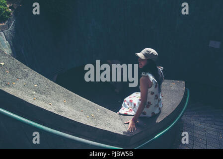 Jeune fille traveler sitting sur circle marches d'un escalier en spirale d'un passage souterrain en tunnel à Fort Canning Park, Singapore Banque D'Images