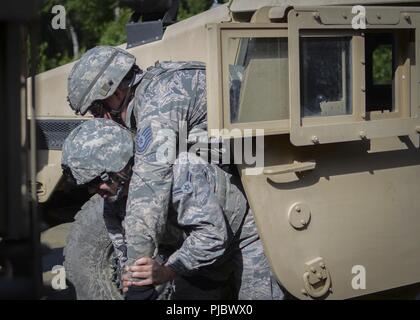 U.S. Air Force d'un membre de la 1re classe Hannah Dennis drags et porte le Sergent Technique. Lawerence Campbell hors d'un Humvee lors d'un convoi à l'exercice Joint Base Elmendorf-Richardson, Ala., 13 juillet 2018. Les Aviateurs, toutes deux affectées à l'Escadron des Forces de sécurité lors de la 128e Escadre de ravitaillement en vol, le Wisconsin Air National Guard, apprenaient à supprimer en toute sécurité du personnel d'un véhicule. Ce convoi a été une partie de la navigation terrestre a participé à la formation d'aviateurs au cours de la mission de formation annuel de l'unité dans l'Alaska. (Air National Guard Banque D'Images