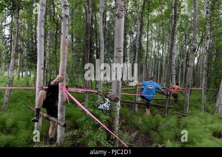 Trois participants font leur chemin à travers l'obstacle en défi au cours de la survie de l'Arctique Mud Run 5k, 16 juillet 2018 à Eielson Air Force Base, en Alaska. D'autres obstacles ont été stratégiquement placés tout au long de la formation en survie dans cette région. Banque D'Images