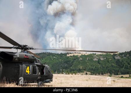 La Garde nationale du Colorado UN UH-60 Black Hawk équipage interrompt leurs efforts de lutte contre les incendies, comme l'espace aérien est effacée, tandis qu'un avion tombe de lisier pour appuyer les efforts de suppression des incendies le 4 juillet 2018. Deux hélicoptères UH-60 Black Hawk avec les équipages des aéronefs, équipés de seaux d'eau, antenne de l'Adjudant chef David R. Carter Aviation de l'Armée de terre et de soutien basé à Buckley Air Force Base, Aurora, Colorado, a appuyé les efforts de suppression des incendies le 4 juillet 2018. L'équipe est arrivée et a commencé ses activités le 2 juillet. Le Cong a soutenu le Feu du printemps depuis le 1er juillet 2018, fournir des capacités à comprendre : Banque D'Images