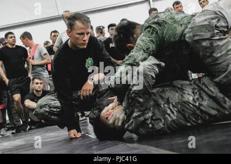 Un soldat de l'armée américaine avec 1er Escadron, 2e Régiment de Cavalerie (à gauche) les arbitres un match bwtween un soldat de l'armée croate avec fusée d'artillerie "Tempête" de batterie, et un soldat britannique avec la 1ère reine Dragoon Guards lors d'un tournoi avec des multinationales combatives au groupe de combat Pologne Bemowo Piskie Domaine de formation, la Pologne le 6 juillet 2018. La Pologne est un groupe de combat, unique coalition multinationale d'États-Unis, Royaume-Uni, croate et soldats roumains qui servent avec la 15e Brigade mécanisée polonaise comme une force de dissuasion de l'OTAN à l'appui de l'amélioration de l'avant la Présence. Banque D'Images