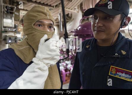 Mer des Philippines (12 juillet 2018) chef-électricien Jose Sarmogenes, droite, un membre de l'équipe de formation en génie, observe-électricien Fireman Lam Nguyen, gauche, rapport demande au cours d'une victime simulée dans un générateur à turbine à gaz prix à bord de la classe Arleigh Burke destroyer lance-missiles USS Benfold (DDG 65). Benfold est l'avant-déployés dans la 7e flotte américaine zone d'opérations à l'appui de la sécurité et de la stabilité dans la région Indo-Pacifique. Banque D'Images