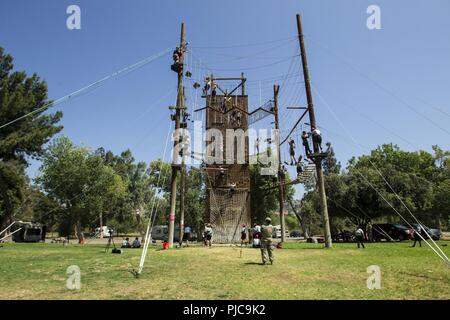 Les candidats dans l'Académie Action Jeunesse Sunburst Class 22 Peloton Firehawks faire leur chemin à travers un système complexe d'obstacles corde en montant à une tyrolienne de terminer, le 19 juillet 2018, à l'Orange County Accrobranche à Anaheim, en Californie. Le parcours donne aux candidats l'occasion de se pousser à la fois mentalement et physiquement, d'instaurer la confiance et de commencer à travailler en équipe tout en restant dans la phase d'acclimatation du défi. Banque D'Images