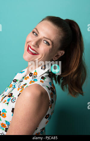 Un cheveux roux Caucasian woman en queue de cheval, portant un mod 60s style earrings pose, un portrait en gros plan. Banque D'Images