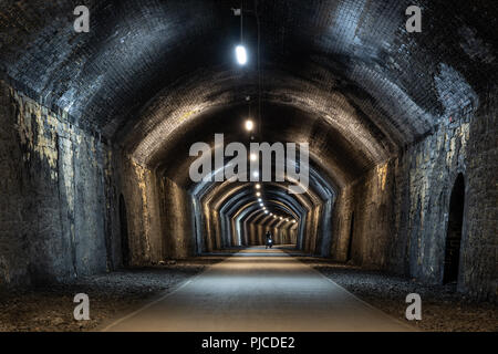 Un cycliste à travers Chee Tor Tunnel sur la piste cyclable, sentier Monsal désaffecté après la Midland Railway dans le Peak District dans Derbsyhire, E Banque D'Images