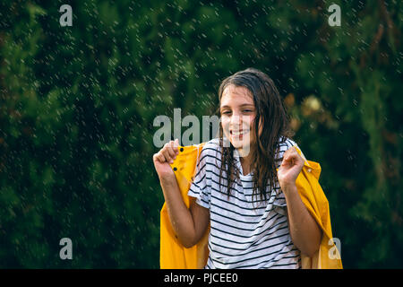 Fille avec imperméable jaune dans la pluie Banque D'Images