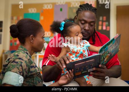 Ricky Jean François, un joueur de football défensif dans la Ligue nationale de football, lit un livre à sa nièce à l'intérieur de la Marine Corps University Library, Marine Corps Base Quantico, en Virginie, le 19 juillet 2018. M. Jean François était en tournée la base avec sa sœur, le major du Corps des Marines des États-Unis Villiana Jean François, officier d'approvisionnement, 4e Groupe logistique maritime, pour aider à promouvoir l'oeuvre et de la santé comportementale et des affaires de la Réserve du Programme de prévention du suicide. Banque D'Images