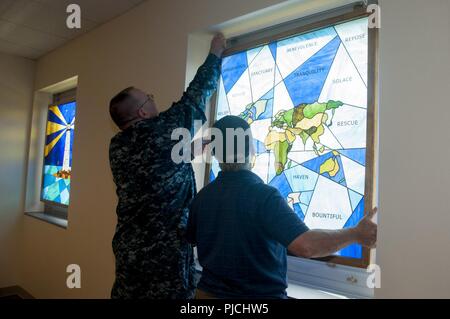 Portsmouth (Virginie (20 juillet 2018) Le Cmdr. Michael Chaney, aumônier du commandement adjoint au Centre médical naval Portsmouth (PNLP), aide Bill Miller de Lumière Vitrail en Poquoson, Virginia, installer le sixième vitrail. La dernière des six vitraux a été installé dans la chapelle du PNLP, marquant une autre étape vers l'achèvement de sa transformation en "Chapelle de confort." Banque D'Images