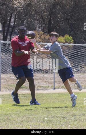 Luc Peay, un joueur de football avec Saint Margaret's Episcopal High School, les captures a football durant une pratique avec les marins de 1er Régiment de Marines, 1 Division de marines au Marine Corps Base Camp Pendleton, en Californie, le 19 juillet 2018. L'événement a fourni des Marines et les écoles secondaires locales la possibilité de maintenir et renforcer les relations communautaires. Banque D'Images