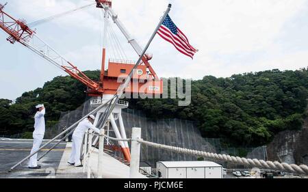 YOKOSUKA, Japon (24 juillet 2018) d'un membre de Paris Alexander, gauche, de Crest View, en Floride, et l'Aviation maître de Manœuvre (manutention) Airman Terrence Garcia, d'El Paso, Texas, hissent le drapeau national sur le poste de pilotage de la marine de l'avant-déployé, porte-avions USS Ronald Reagan (CVN 76), qu'il tire en commandant, activités liées à la flotte de Yokosuka après une patrouille. Ronald Reagan, le groupe aéronaval du porte-étendard de 5, fournit une force prête au combat qui protège et défend les intérêts de maritime collective de ses alliés et partenaires dans la région Indo-Pacifique. Banque D'Images