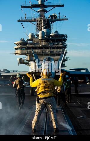 Mer des Philippines (20 juillet 2018) l'aviation en chef Maître de Manœuvre (manutention) Darrio Davis, de Baltimore, diriger un F/A-18E Super Hornet affectés à l'Escadron d'avions de combat interarmées (VFA) 195 dans le poste de pilotage de la marine de l'avant-déployé, porte-avions USS Ronald Reagan (CVN 76). Ronald Reagan, le groupe aéronaval du porte-étendard de 5, fournit une force prête au combat qui protège et défend les intérêts de maritime collective de ses alliés et partenaires dans la région Indo-Pacifique. Banque D'Images