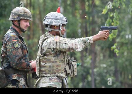 Un soldat américain, à droite, avec le 18e Bataillon de soutien au maintien en puissance de combat tire un pistolet P8 au cours d'une formation sur les armes allemandes, la familiarisation et l'épreuve de qualification pour démontrer l'interopérabilité et de renforcer le partenariat de la cohésion sociale à la 7e Armée, le commandement de l'aire d'entraînement Grafenwoehr, Allemagne, le 20 juillet 2018. Banque D'Images