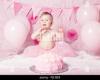 Portrait of cute adorable Caucasian baby girl with blue eyes en jupe tutu rose fête son premier anniversaire avec gâteau gastronomique et des ballons à Banque D'Images