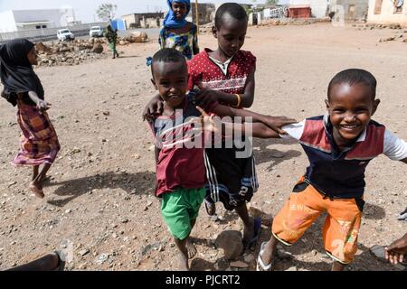 L'enfant djiboutien local posent pour une photo alors que les soldats de l'Armée américaine affecté à la 404e Bataillon des affaires civiles mener une étude de site pour évaluer les projets en cours de construction à Holh Hol , Djibouti, le 24 juillet 2018. Grâce à l'engagement du chef du Bureau des affaires civiles, l'équipe travaille à améliorer encore les relations entre le local national peuplé et les forces américaines. Banque D'Images