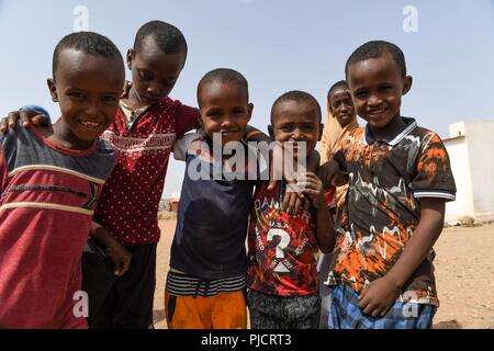 L'enfant djiboutien local posent pour une photo alors que les soldats de l'Armée américaine affecté à la 404e Bataillon des affaires civiles mener une étude de site pour évaluer les projets en cours de construction à Holh Hol, Djibouti, le 24 juillet 2018. Grâce à l'engagement du chef du Bureau des affaires civiles, l'équipe travaille à améliorer encore les relations entre le local national peuplé et les forces américaines. Banque D'Images