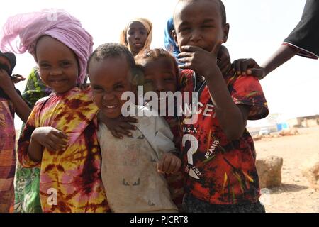 L'enfant djiboutien local posent pour une photo alors que les soldats de l'Armée américaine affecté à la 404e Bataillon des affaires civiles mener une étude de site pour évaluer les projets en cours de construction à Holh Hol, Djibouti, le 24 juillet 2018. Grâce à l'engagement du chef du Bureau des affaires civiles, l'équipe travaille à améliorer encore les relations entre le local national peuplé et les forces américaines. Banque D'Images