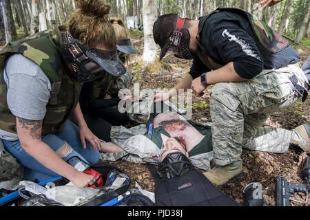 Le personnel du 673d Medical Group recherche des blessures au cours de l'application pratique de la situation de combat tactique à l'extrême au cours de Paintball Warrior Joint Base Elmendorf-Richardson, Alaska, le 13 juillet 2018. Le cours est l'occasion pour chaque étudiant de fournir des soins sous le feu, effectuer des soins sur le terrain tactique sur ceux qui sont blessés et exécuter une évacuation tactique. Banque D'Images