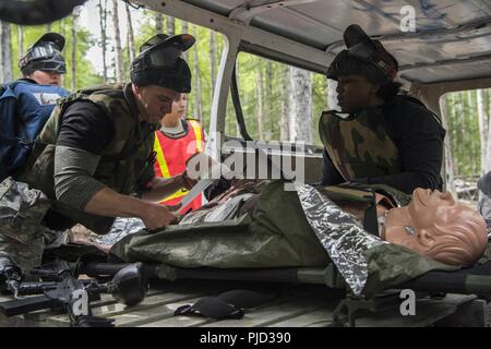 Le personnel du 673d Medical Group couvrir les blessures d'un patient "blessés" lors de l'application pratique de la situation de combat tactique à l'extrême au cours de Paintball Warrior Joint Base Elmendorf-Richardson, Alaska, le 13 juillet 2018. Le cours est l'occasion pour chaque étudiant de fournir des soins sous le feu, effectuer des soins sur le terrain tactique sur ceux qui sont blessés et exécuter une évacuation tactique. Banque D'Images