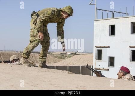 Le caporal de l'armée australienne. Perrie Irwin, un groupe de formateurs de Taji, rire avec un soldat iraquien au cours en zone urbaine avec 2e Bataillon, 59e Brigade, au Camp Taji, l'Iraq, le 17 juillet 2018. Activé par une accélération des succès contre ISIS en 2017, Coalition pour soutenir nos partenaires évolue comme nous aider nos partenaires pour assurer la sécurité qui permet aux efforts de stabilisation. Banque D'Images