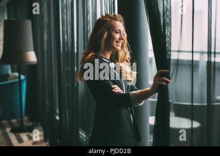 Glamorous woman staring through window Banque D'Images