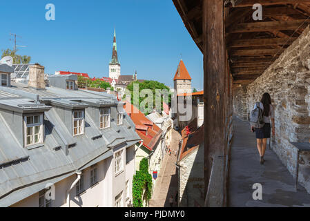 L'Estonie le tourisme, une jeune femme voyageur solo promenades le long de la galerie supérieure de la tour médiévale Hellemann et mur de ronde à Tallinn, Estonie. Banque D'Images