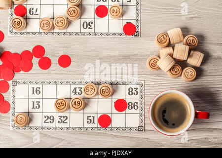 Jeu de loto. Jeu de lotto en bois de barils, cartes, jetons rouges et tasse de café. Vue d'en haut Banque D'Images