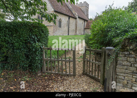 Vieilles portes de bois et un chemin de gravier menant à l'église historique de St Mary, dans le village de Cold Brayfield, Bedfordshire, Royaume-Uni Banque D'Images