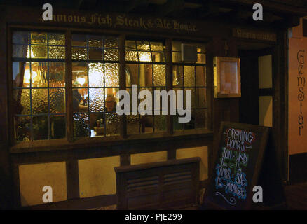 Devon. Centre-ville pub sur un soir d'hivers froids, un visage dans les fenêtres est relaxant avec un verre Banque D'Images