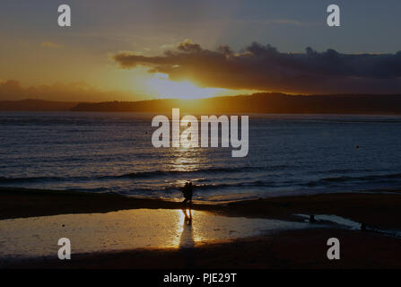 La dernière marche de la journée au coucher du soleil, pour un couple, en hiver sur la plage d'Exmouth dans le Devon en Angleterre Banque D'Images