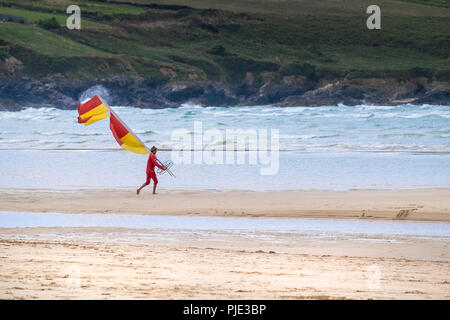 Un sauveteur RNLI déplacer un marqueur de sécurité drapeau sur la plage de Crantock en Newquay Cornwall. Banque D'Images