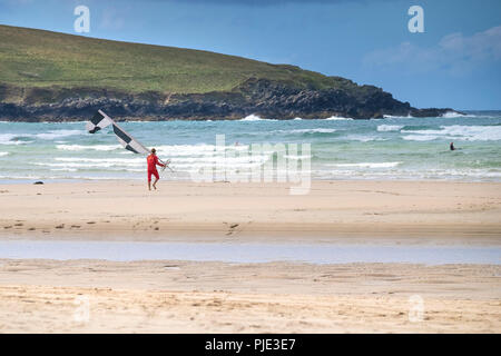 Un sauveteur RNLI déplacer un marqueur de sécurité drapeau sur la plage de Crantock en Newquay Cornwall. Banque D'Images